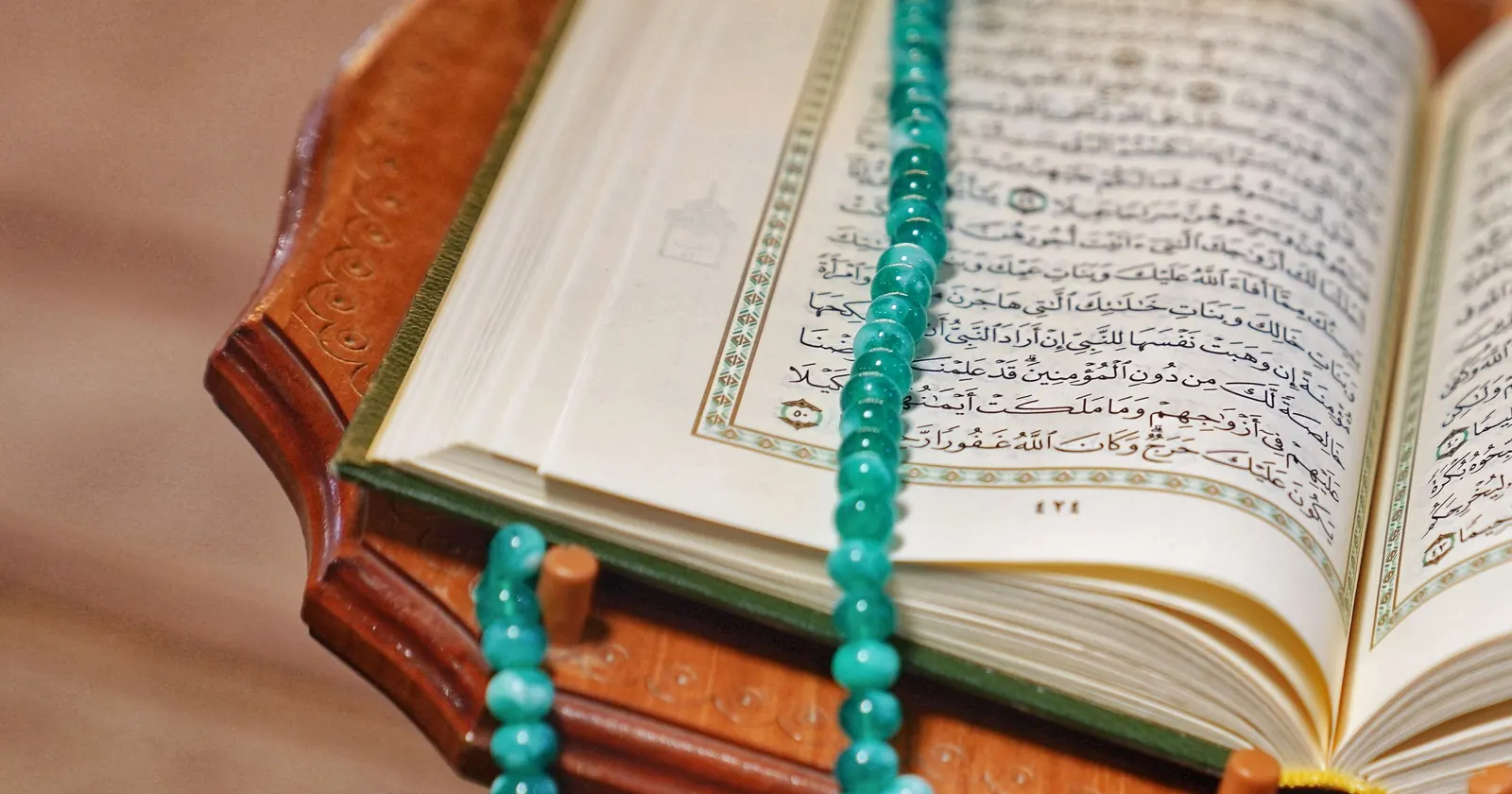 Ahşap rahle üzerinde açık Kur'an-ı Kerim ve turkuaz tespih