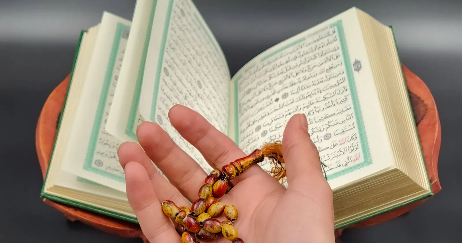 Açık Kur'an-ı Kerim ve avuç içinde tutulan tespih